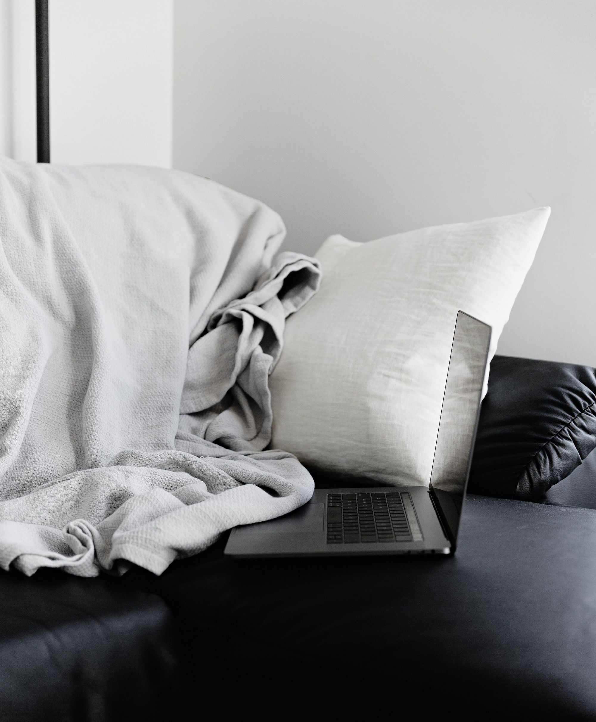 Ordinateur portable sur un lit avec oreiller et draps.